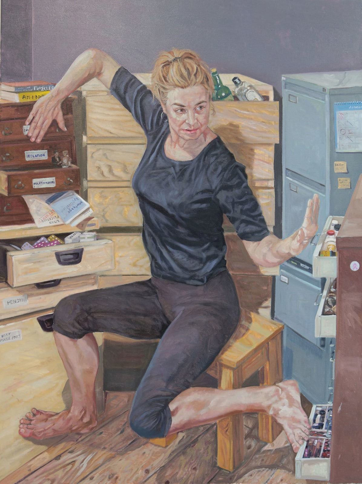 Woman sitting on a stool in a cluttered room with drawers and a filing cabinets.